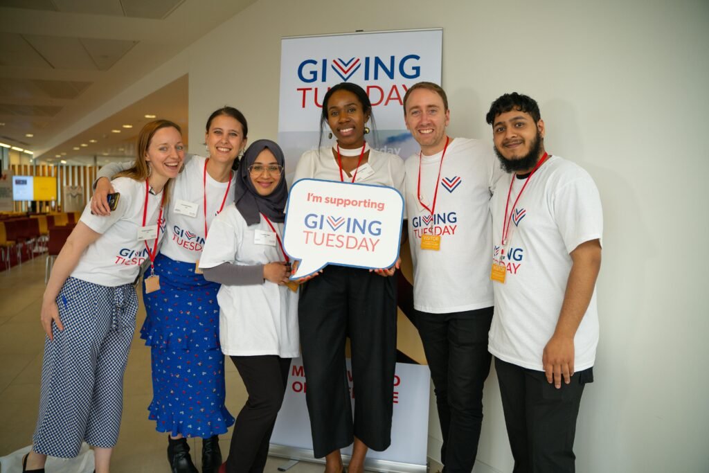 Diverse group of adults supporting Giving Tuesday with enthusiasm indoors.